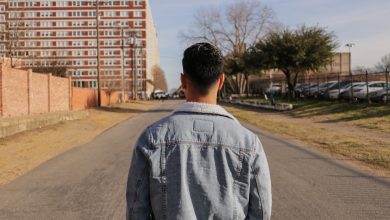 man standing in gray pathway near buildings